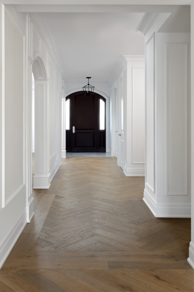 Aménagement d'une grande entrée classique avec un couloir, un mur blanc, un sol en bois brun, un sol marron et du lambris.