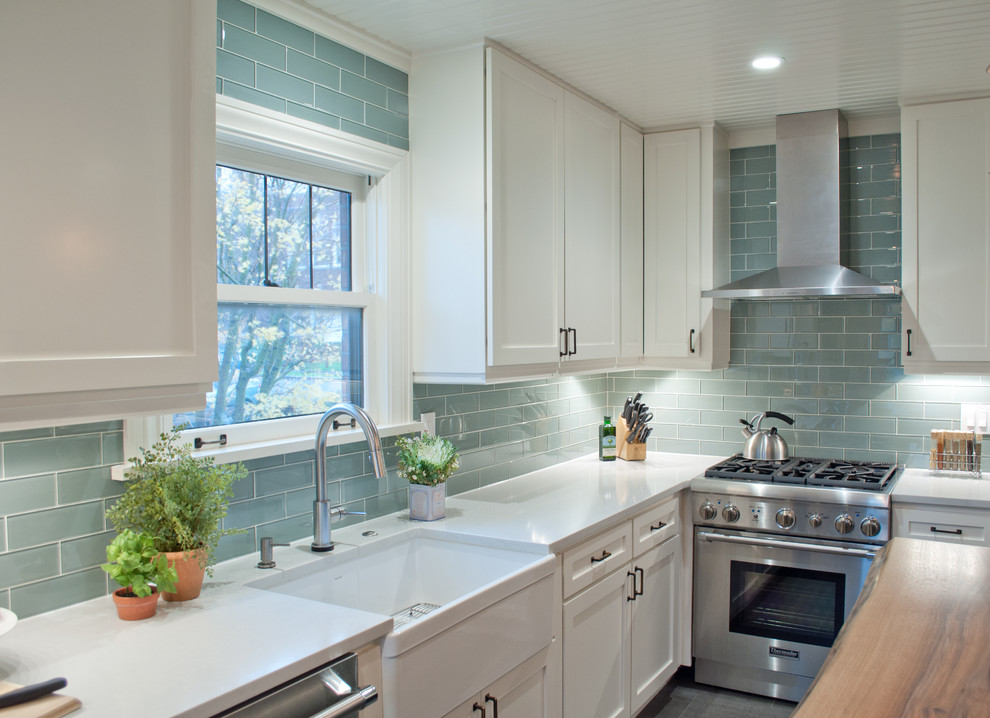 This is an example of a small transitional u-shaped separate kitchen in Seattle with a farmhouse sink, shaker cabinets, white cabinets, quartzite benchtops, blue splashback, glass tile splashback, stainless steel appliances, porcelain floors, with island and grey floor.