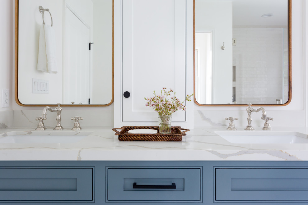 Inspiration for a mid-sized contemporary master bathroom in Los Angeles with a freestanding tub, an undermount sink, shaker cabinets, blue cabinets, a corner shower, beige tile, subway tile, white walls, porcelain floors, marble benchtops, white floor and a hinged shower door.