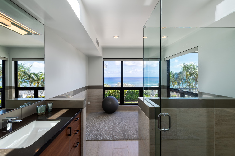 Photo of a large modern master bathroom in Hawaii with porcelain tile, porcelain floors, an undermount sink, beige floor, a hinged shower door, flat-panel cabinets, medium wood cabinets, an alcove shower, beige tile and granite benchtops.