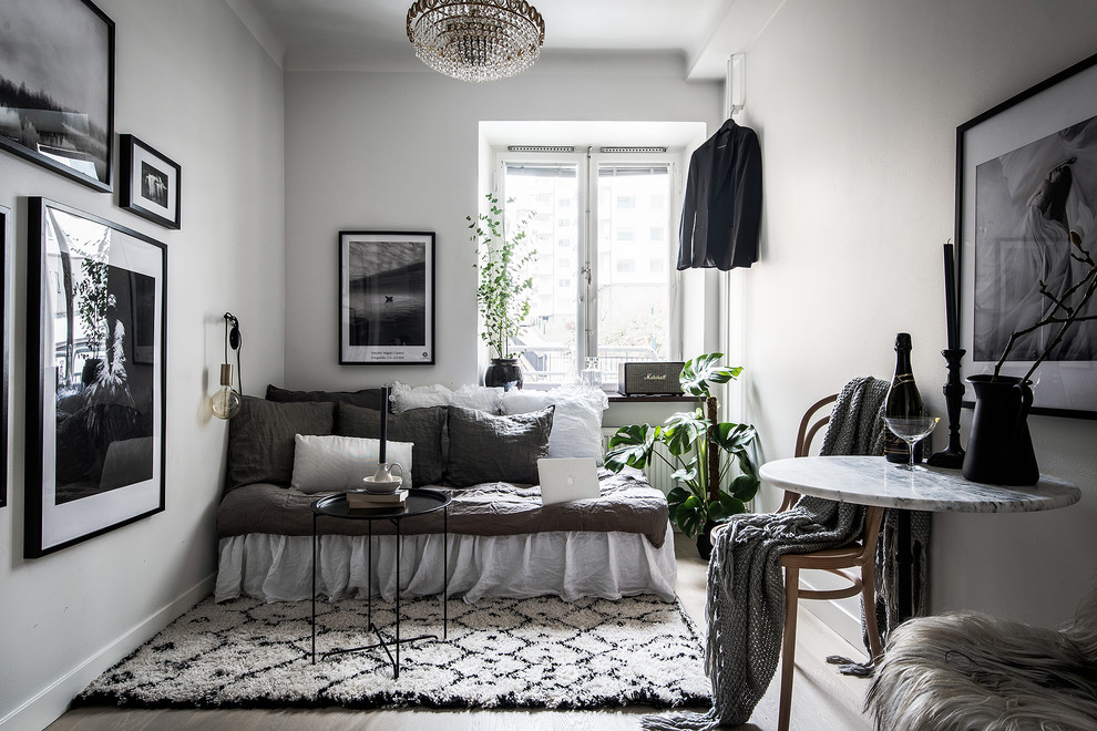 This is an example of a mid-sized scandinavian open concept living room in Stockholm with white walls, no tv and light hardwood floors.