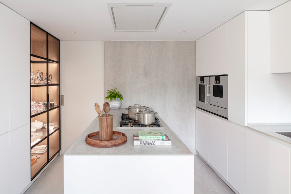 Inredning av ett modernt mellanstort grå grått kök, med en nedsänkt diskho, luckor med infälld panel, grå skåp, bänkskiva i rostfritt stål, grått stänkskydd, stänkskydd i kalk, integrerade vitvaror, ljust trägolv, en halv köksö och grått golv