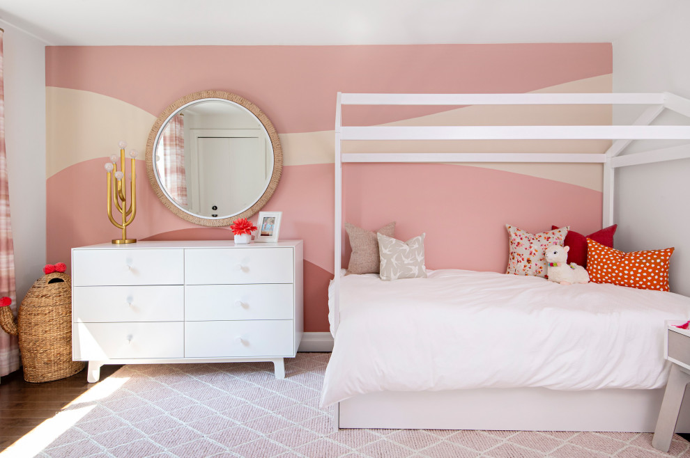 Modern inredning av ett mellanstort barnrum kombinerat med sovrum, med rosa väggar, mellanmörkt trägolv och brunt golv