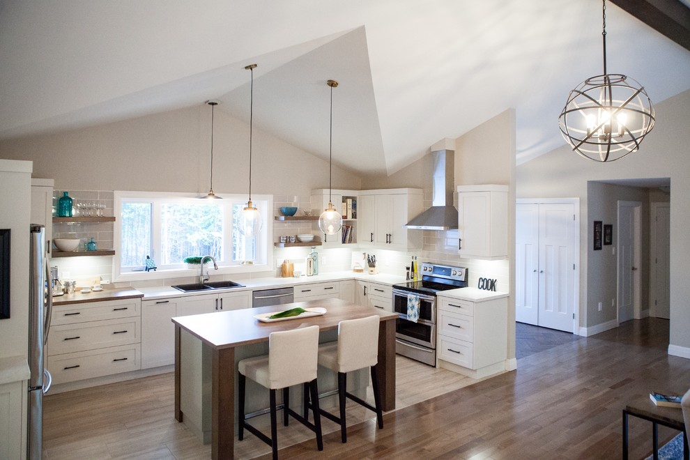 Mid-sized minimalist u-shaped medium tone wood floor and brown floor open concept kitchen photo with a drop-in sink, shaker cabinets, white cabinets, quartz countertops, gray backsplash, ceramic backsplash, stainless steel appliances, an island and white countertops