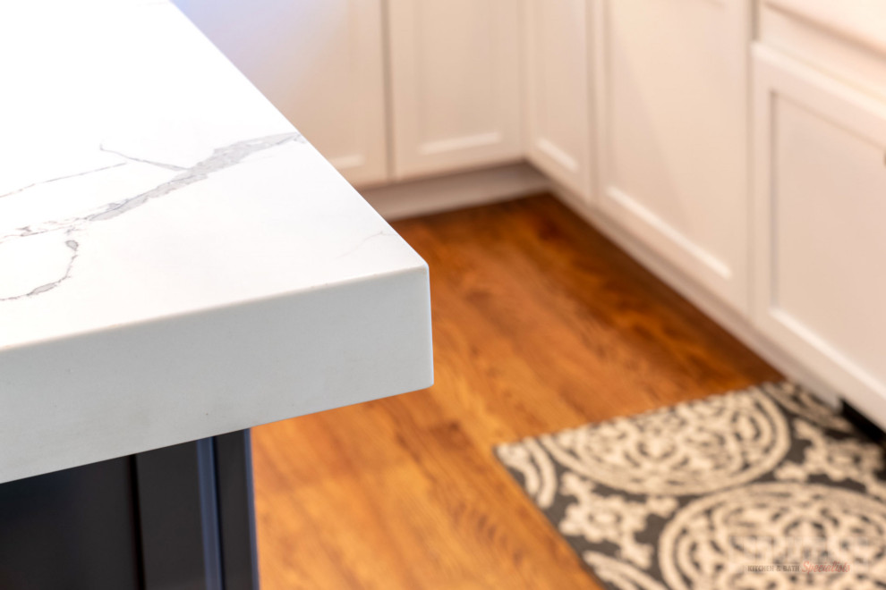 Inspiration for a mid-sized transitional l-shaped medium tone wood floor and brown floor eat-in kitchen remodel in New York with a farmhouse sink, recessed-panel cabinets, white cabinets, quartzite countertops, multicolored backsplash, stainless steel appliances, an island and multicolored countertops