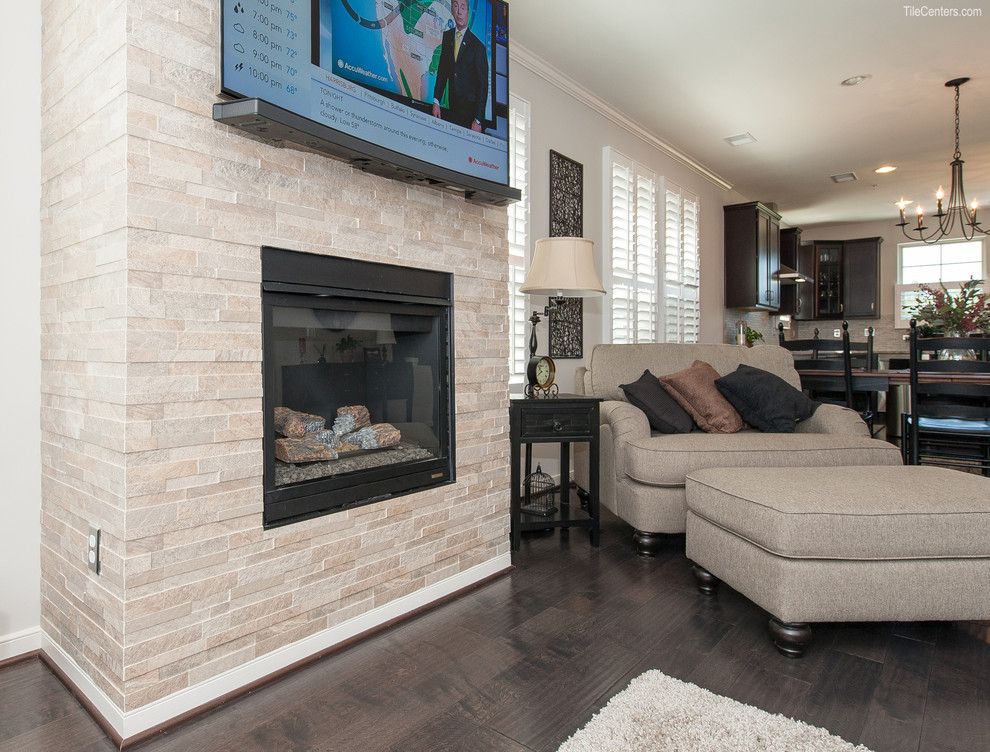 Inspiration for a mid-sized transitional enclosed living room in DC Metro with beige walls, medium hardwood floors, a standard fireplace, a stone fireplace surround, a wall-mounted tv and brown floor.