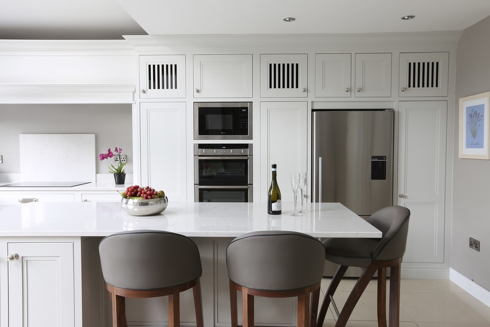 Inspiration for a mid-sized transitional l-shaped eat-in kitchen in Dublin with an undermount sink, beaded inset cabinets, grey cabinets, quartz benchtops, white splashback, stone slab splashback, stainless steel appliances, porcelain floors and with island.