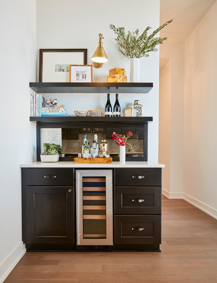 Design ideas for a small transitional single-wall wet bar in Chicago with dark wood cabinets, quartz benchtops, mirror splashback, medium hardwood floors, shaker cabinets, brown floor and no sink.