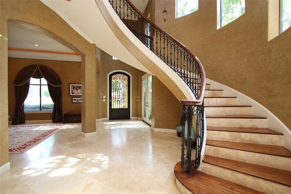 Design ideas for an expansive mediterranean wood floating staircase in Houston with travertine risers and mixed railing.