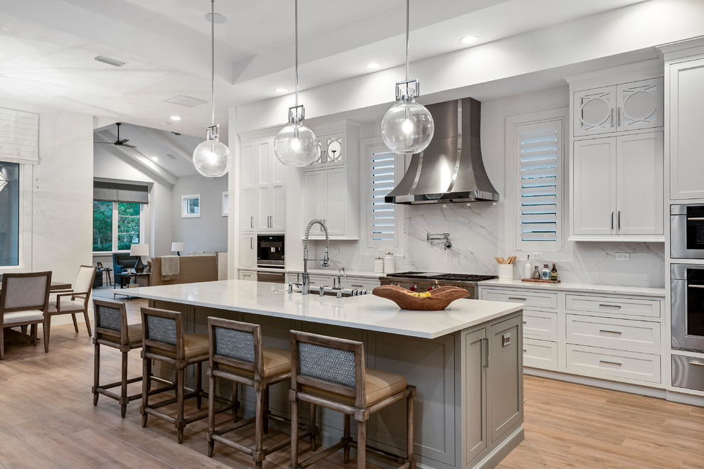 Inspiration for a transitional galley kitchen in Orlando with an undermount sink, shaker cabinets, white cabinets, stainless steel appliances, medium hardwood floors, with island, brown floor and white benchtop.