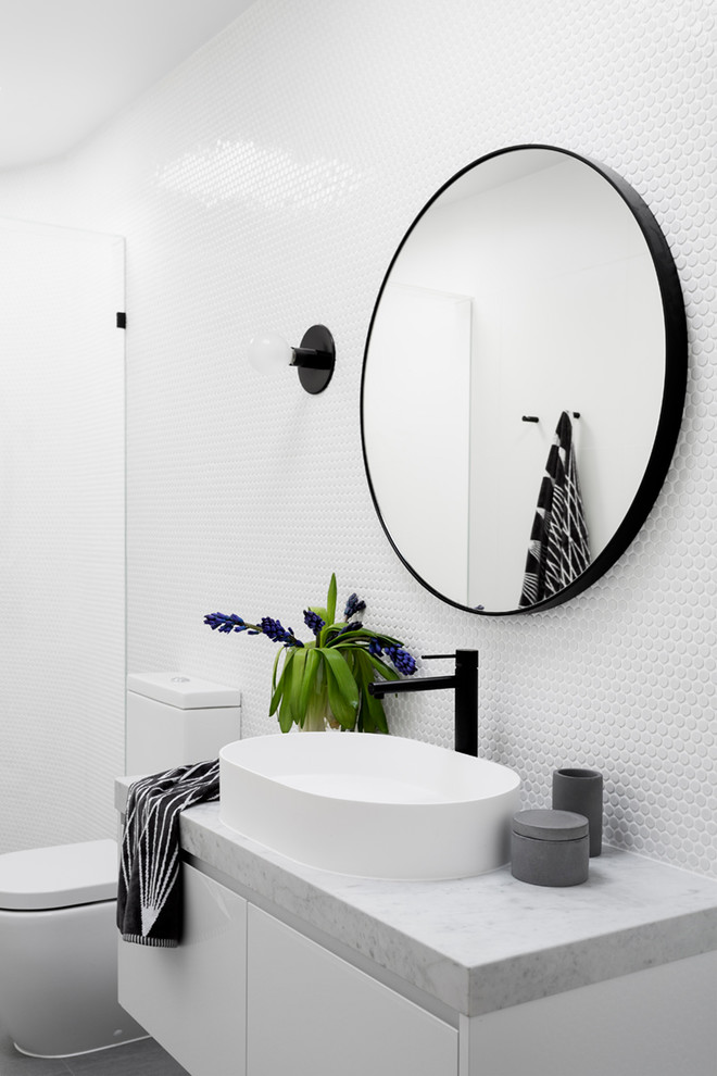Mid-sized contemporary 3/4 bathroom in Melbourne with flat-panel cabinets, white cabinets, an alcove shower, a one-piece toilet, white tile, mosaic tile, white walls, porcelain floors, a vessel sink, marble benchtops, grey floor and a hinged shower door.