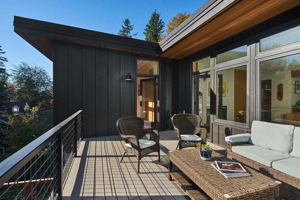 Inspiration for a large midcentury two-storey black house exterior in Portland with wood siding, a butterfly roof and board and batten siding.