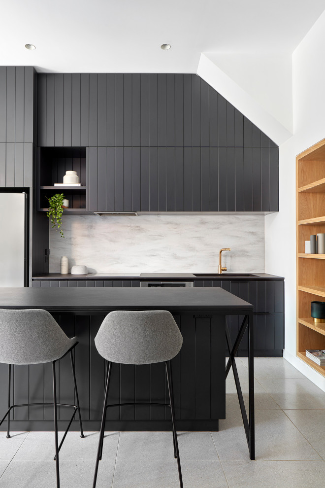 This is an example of a large contemporary l-shaped kitchen in Melbourne with an integrated sink, black cabinets, grey splashback, stainless steel appliances, with island, grey floor, black benchtop and flat-panel cabinets.