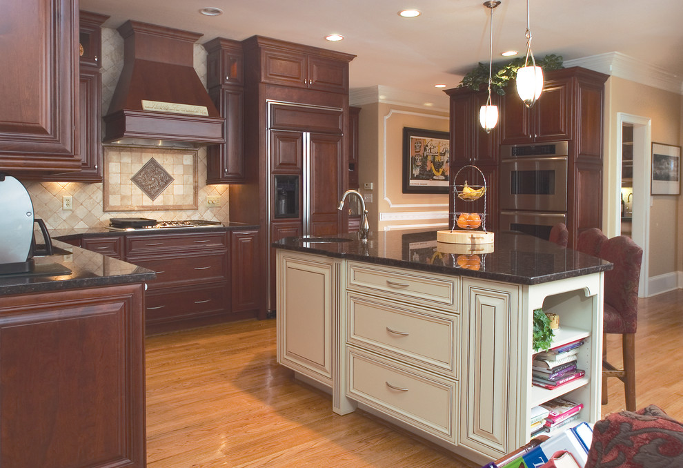 Design ideas for a large traditional u-shaped eat-in kitchen in Atlanta with an undermount sink, raised-panel cabinets, dark wood cabinets, granite benchtops, beige splashback, stone tile splashback, stainless steel appliances, medium hardwood floors and with island.