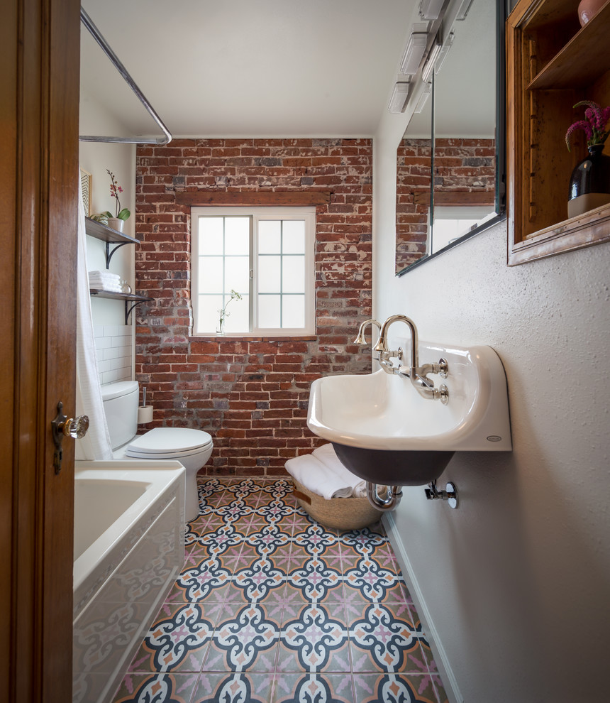 Small industrial bathroom in Denver with a corner tub, a shower/bathtub combo, white tile, subway tile, white walls, a wall-mount sink, multi-coloured floor, a shower curtain, porcelain floors and a single vanity.