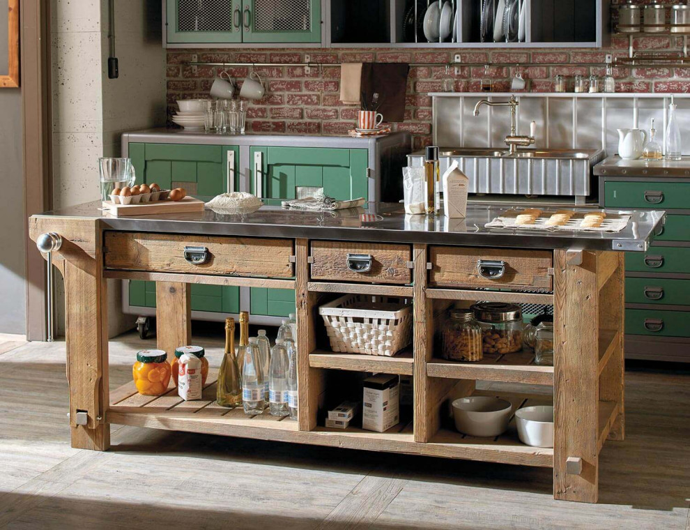 Inspiration for a medium sized rustic single-wall kitchen/diner in Austin with stainless steel appliances, stainless steel worktops, an island, grey worktops, a belfast sink, louvered cabinets, green cabinets, grey splashback, brick splashback, light hardwood flooring, brown floors and exposed beams.