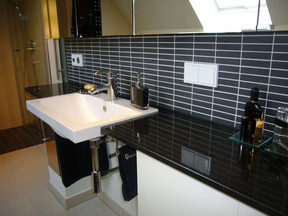Traditional bathroom in Berlin with flat-panel cabinets, white cabinets, black tile, mosaic tile, pebble tile floors, a drop-in sink, stainless steel benchtops and beige floor.