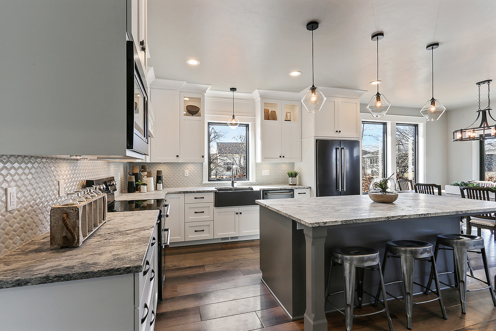 Traditional eat-in kitchen in Milwaukee with a farmhouse sink, flat-panel cabinets, white cabinets, quartz benchtops, white splashback, ceramic splashback, black appliances, medium hardwood floors, with island and brown floor.