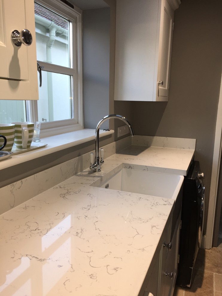 Photo of a small traditional galley utility room in Wiltshire with a farmhouse sink, quartz benchtops and grey walls.