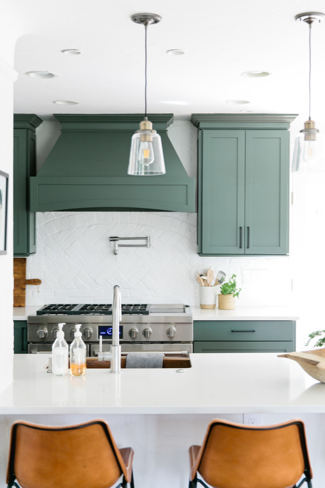 Mid-sized transitional galley medium tone wood floor and brown floor eat-in kitchen photo in Denver with a farmhouse sink, shaker cabinets, green cabinets, quartz countertops, white backsplash, brick backsplash, stainless steel appliances, a peninsula and white countertops