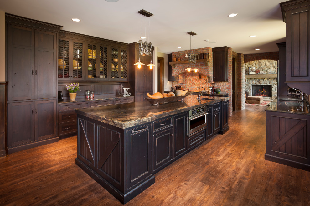 Example of a large mountain style u-shaped medium tone wood floor and brown floor kitchen design in Detroit with an undermount sink, shaker cabinets, dark wood cabinets, brown backsplash, wood backsplash, stainless steel appliances, an island and brown countertops