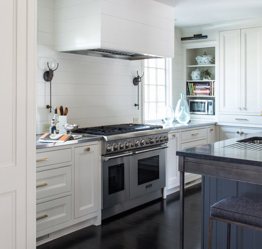 Large transitional u-shaped dark wood floor enclosed kitchen photo with an undermount sink, recessed-panel cabinets, white cabinets, granite countertops, white backsplash, stainless steel appliances and an island