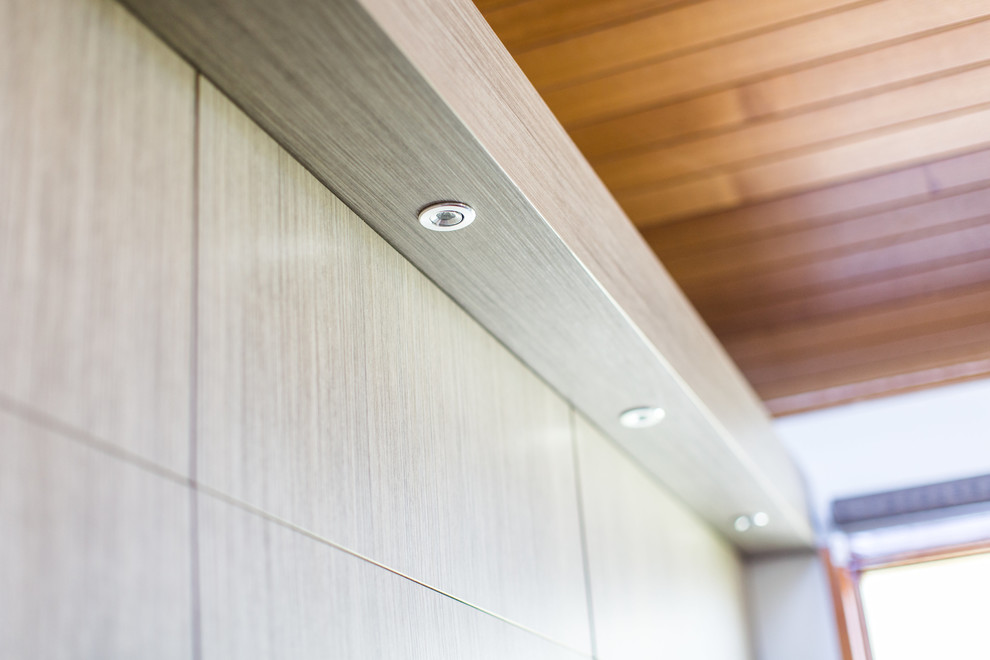 Design ideas for a large contemporary u-shaped kitchen in Canberra - Queanbeyan with a double-bowl sink, flat-panel cabinets, light wood cabinets, quartz benchtops, beige splashback, glass sheet splashback, stainless steel appliances, terra-cotta floors, brown floor and black benchtop.