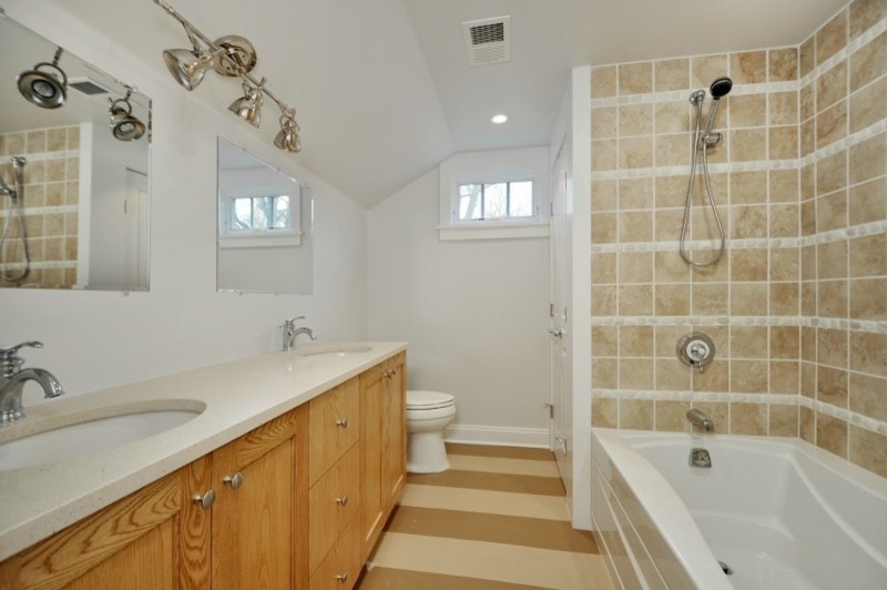 Inspiration for a mid-sized beach style master bathroom in New York with recessed-panel cabinets, light wood cabinets, a shower/bathtub combo, a two-piece toilet, beige tile, white walls, cork floors, an undermount sink, multi-coloured floor, an open shower, beige benchtops, engineered quartz benchtops, pebble tile and an alcove tub.