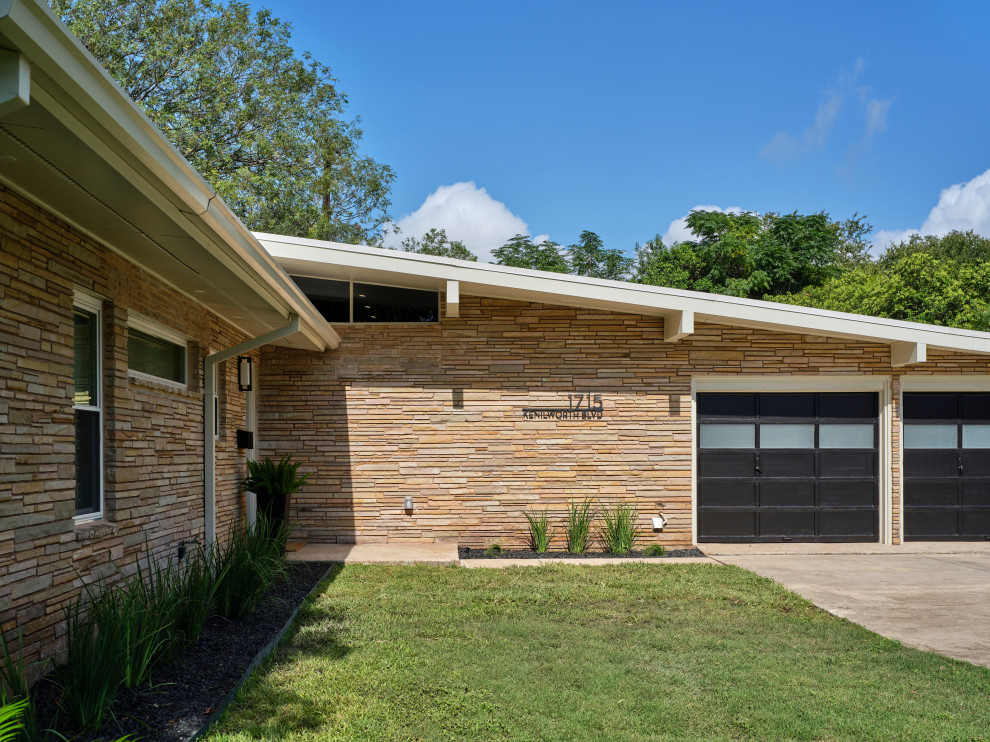 Medium sized and beige retro bungalow detached house in Austin with stone cladding, a flat roof, a mixed material roof and a black roof.