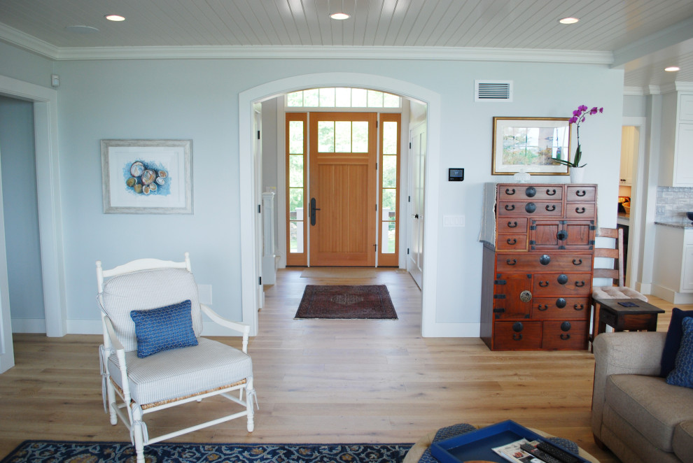 Exemple d'un grand hall d'entrée bord de mer avec un mur bleu, parquet clair, une porte simple, une porte en bois brun et un plafond en lambris de bois.