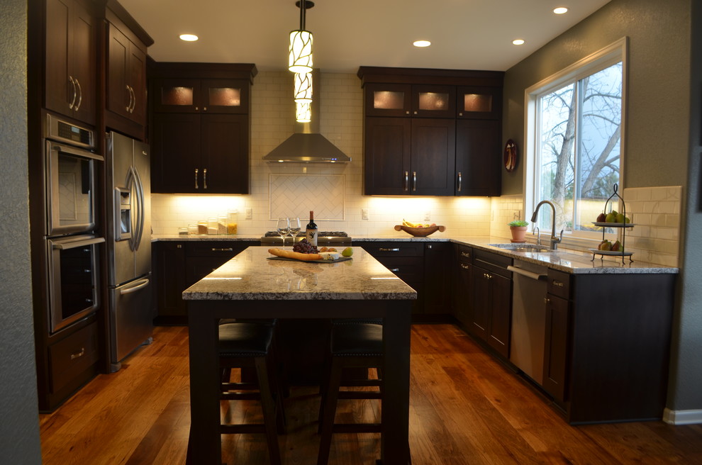 Kitchen - transitional medium tone wood floor kitchen idea in Denver with an undermount sink, shaker cabinets, dark wood cabinets, granite countertops, white backsplash, subway tile backsplash, stainless steel appliances and an island