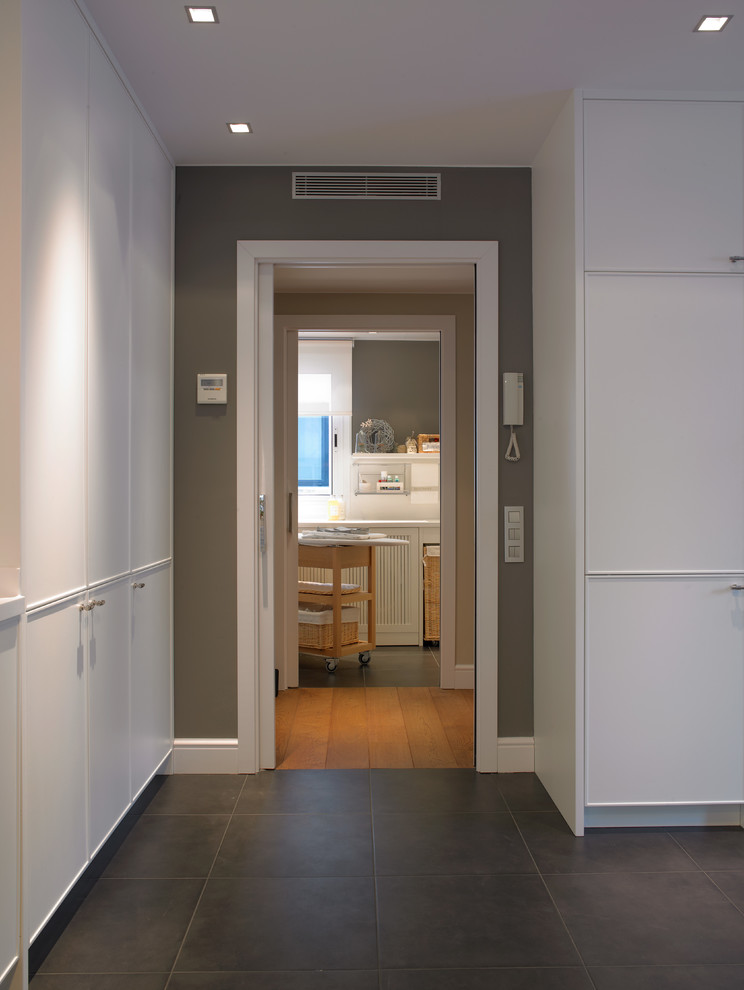 Mid-sized contemporary laundry room in Barcelona with white cabinets.