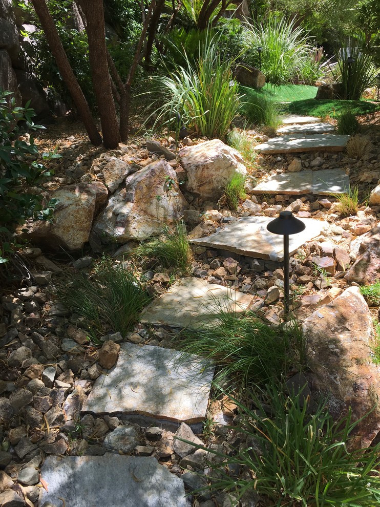 Inspiration for an expansive tropical backyard garden in Las Vegas with a water feature and natural stone pavers.