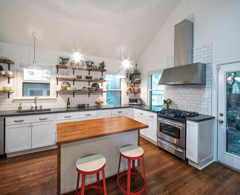 Photo of a midcentury l-shaped separate kitchen in Austin with an undermount sink, shaker cabinets, white cabinets, concrete benchtops, white splashback, porcelain splashback, stainless steel appliances, light hardwood floors and with island.