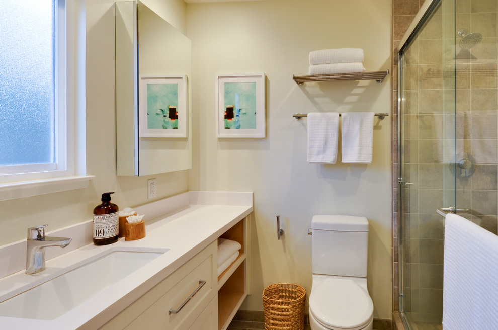 This is an example of a mid-sized transitional 3/4 bathroom in San Francisco with shaker cabinets, white cabinets, an alcove shower, a two-piece toilet, beige tile, stone tile, beige walls, limestone floors, an undermount sink and quartzite benchtops.