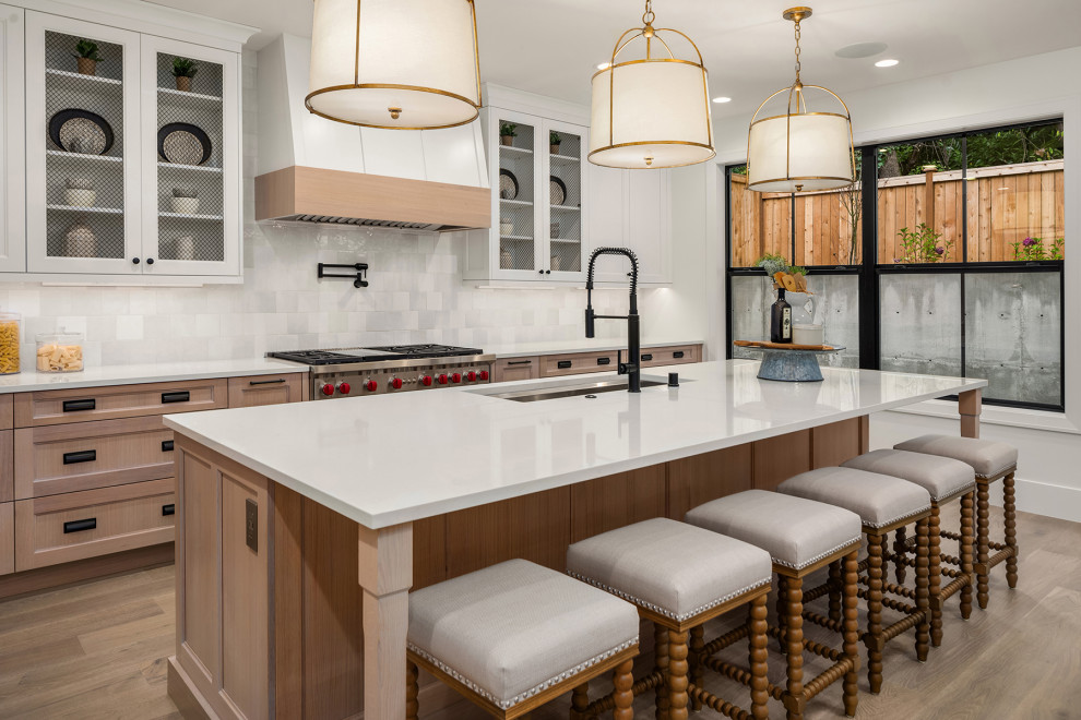 Inspiration for a large country eat-in kitchen in Seattle with an undermount sink, recessed-panel cabinets, light wood cabinets, quartz benchtops, white splashback, porcelain splashback, panelled appliances, medium hardwood floors, with island and white benchtop.