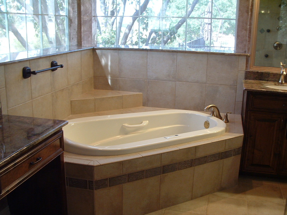 Example of a large transitional master beige tile and ceramic tile ceramic tile drop-in bathtub design in Dallas with raised-panel cabinets, dark wood cabinets, beige walls, an undermount sink and marble countertops