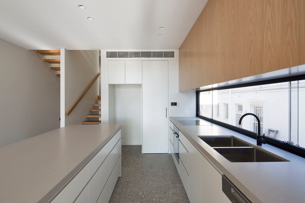 Mid-sized contemporary galley kitchen pantry in Sydney with flat-panel cabinets, quartz benchtops, concrete floors, with island and beige benchtop.