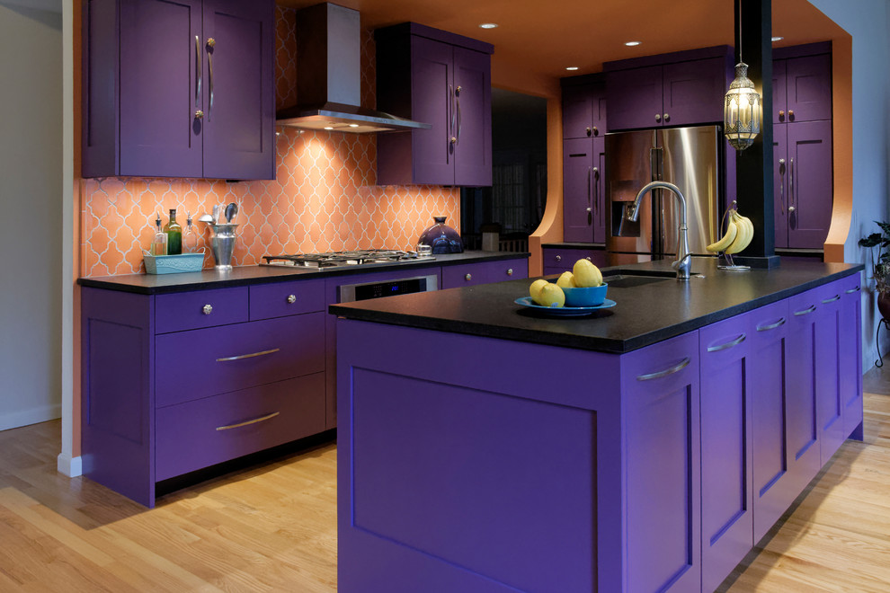 Inspiration for a large eclectic galley eat-in kitchen in Portland with an undermount sink, shaker cabinets, purple cabinets, solid surface benchtops, orange splashback, ceramic splashback, stainless steel appliances, light hardwood floors and with island.