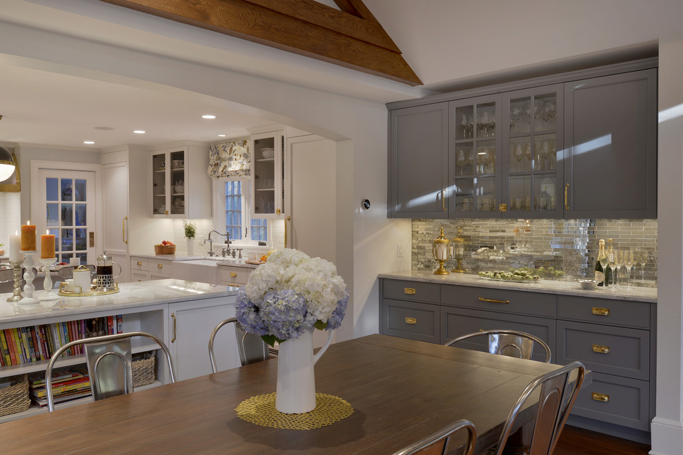 Expansive transitional l-shaped eat-in kitchen in New York with a farmhouse sink, quartzite benchtops, dark hardwood floors, multiple islands, glass-front cabinets, grey cabinets, metallic splashback and mirror splashback.