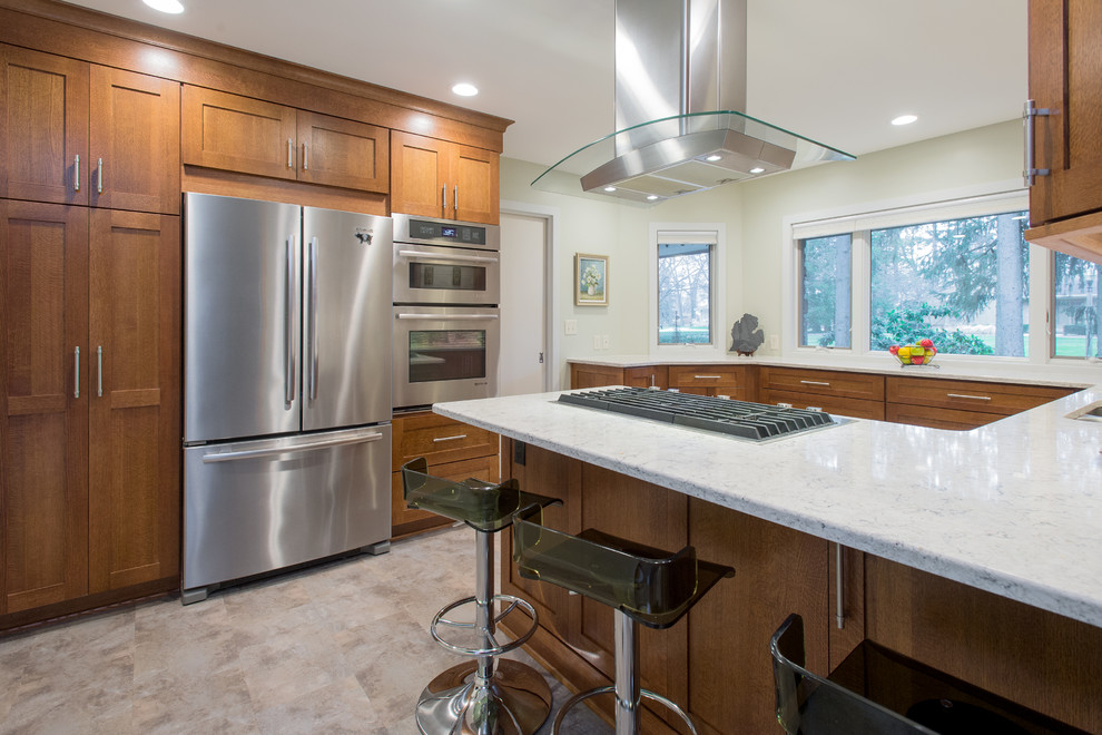 Large contemporary u-shaped eat-in kitchen in Grand Rapids with an undermount sink, shaker cabinets, dark wood cabinets, granite benchtops, stainless steel appliances, with island, multi-coloured splashback, matchstick tile splashback and porcelain floors.