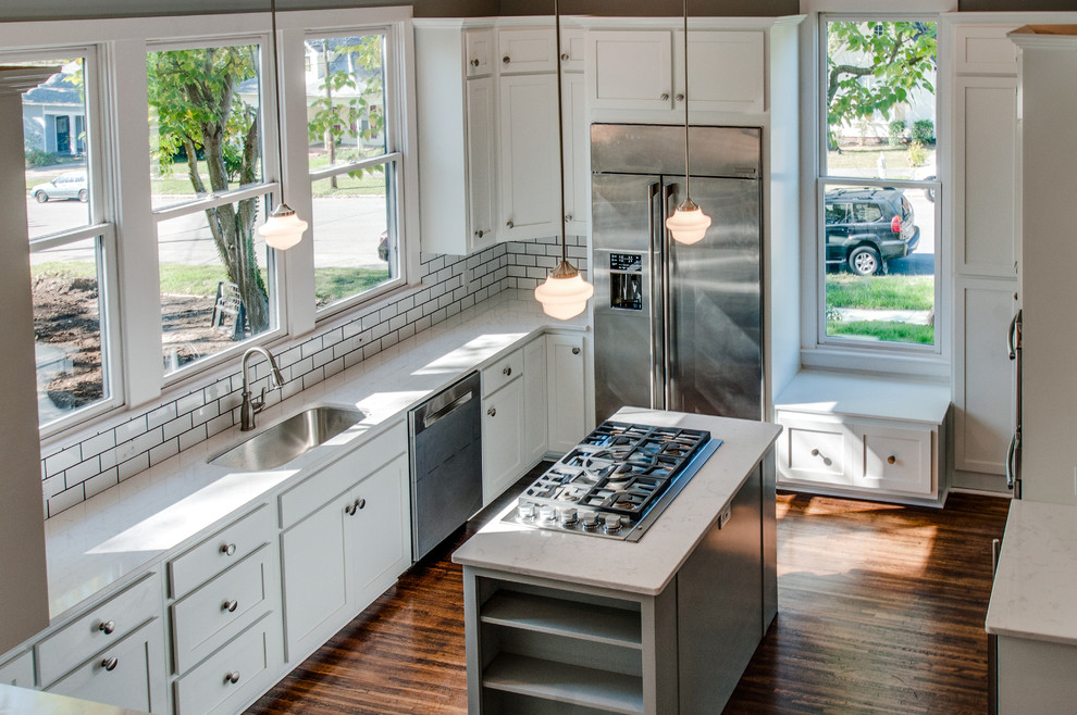 Photo of a mid-sized traditional u-shaped separate kitchen in Nashville with an undermount sink, shaker cabinets, white cabinets, quartz benchtops, white splashback, subway tile splashback, stainless steel appliances, dark hardwood floors and with island.