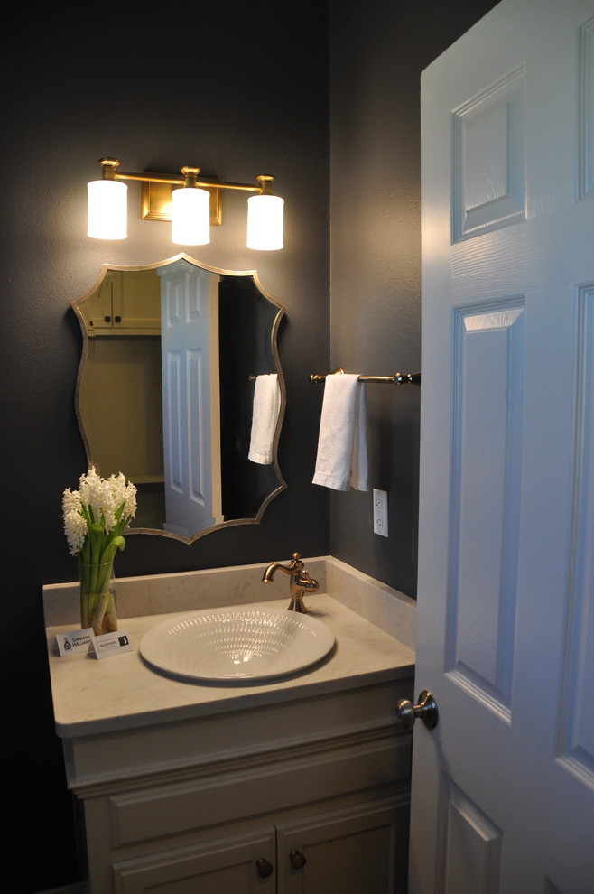 Small transitional powder room in New Orleans with blue walls, recessed-panel cabinets, a vessel sink and beige cabinets.