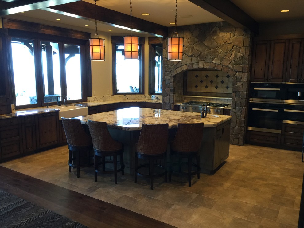 Example of a large mountain style u-shaped eat-in kitchen design in Seattle with a farmhouse sink, flat-panel cabinets, dark wood cabinets, gray backsplash, stone tile backsplash, stainless steel appliances and an island