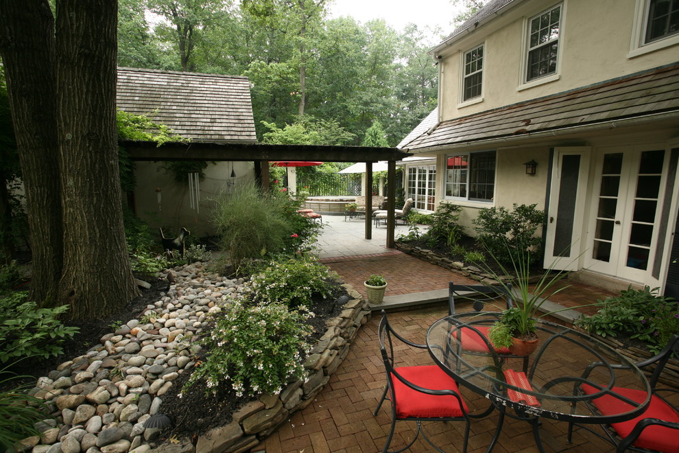 This is an example of a traditional patio in Philadelphia with brick pavers and no cover.