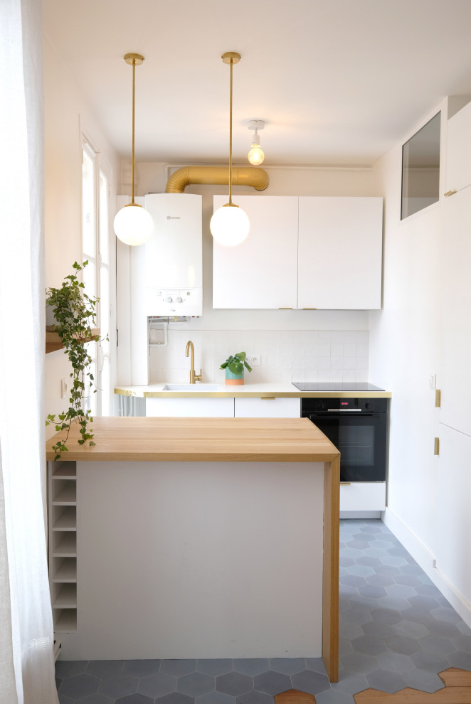 This is an example of a small midcentury galley open plan kitchen in Paris with a submerged sink, flat-panel cabinets, white cabinets, laminate countertops, white splashback, ceramic splashback, integrated appliances, ceramic flooring, an island, blue floors and white worktops.