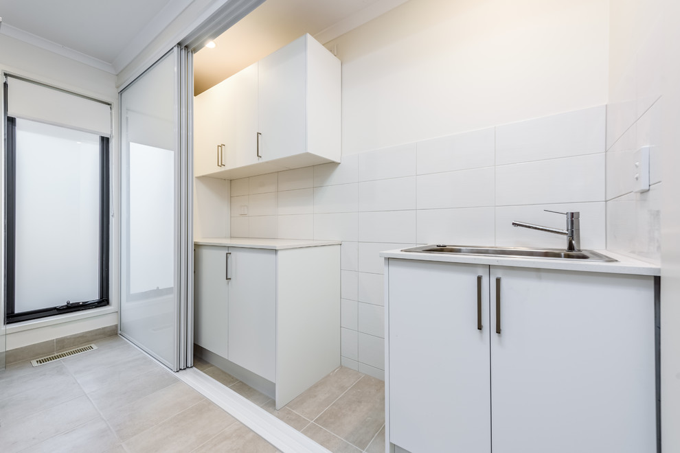 Photo of a small contemporary single-wall laundry room in Melbourne with white walls, ceramic floors and beige floor.