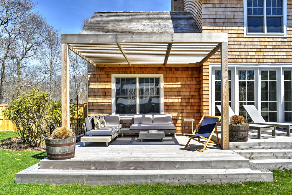 Photo of a beach style deck in New York with a pergola.