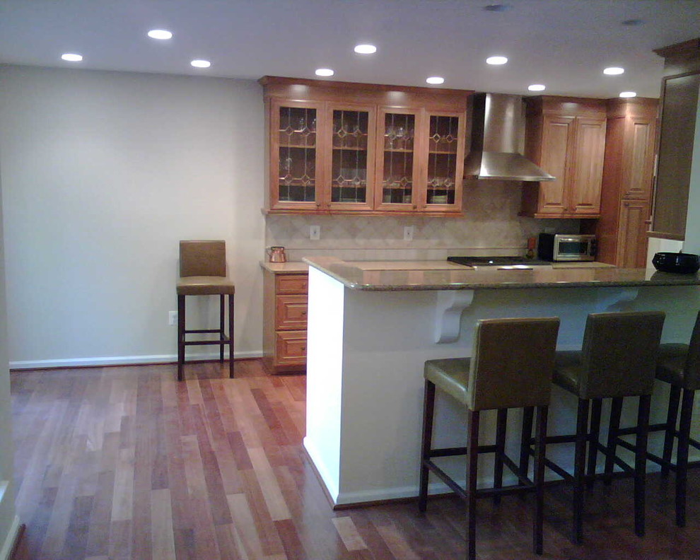 Example of a medium tone wood floor kitchen design in DC Metro with medium tone wood cabinets, beige backsplash and stainless steel appliances