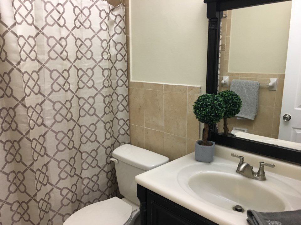 Design ideas for a small traditional master bathroom in Miami with black cabinets, an alcove shower, beige walls, an integrated sink, solid surface benchtops and a shower curtain.